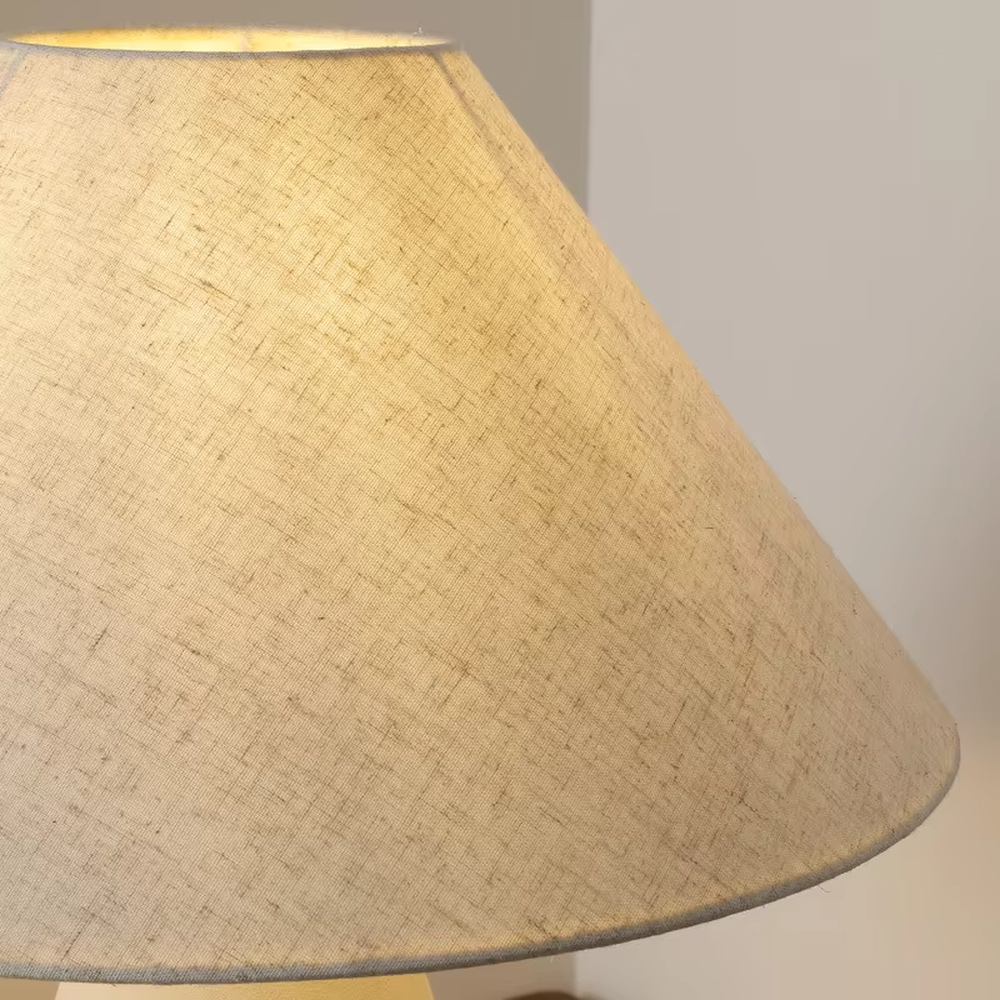 This is a wabi-sabi style minimalist table lamp, featuring an off-white frosted ceramic base paired with a linen fabric lampshade. The light is soft and warm, serving both lighting and decorative purposes, suitable for scenarios pursuing a warm and relaxed feeling such as bedroom nightstands, homestay guest rooms, Japanese-style tea rooms, and wabi-sabi style living rooms.