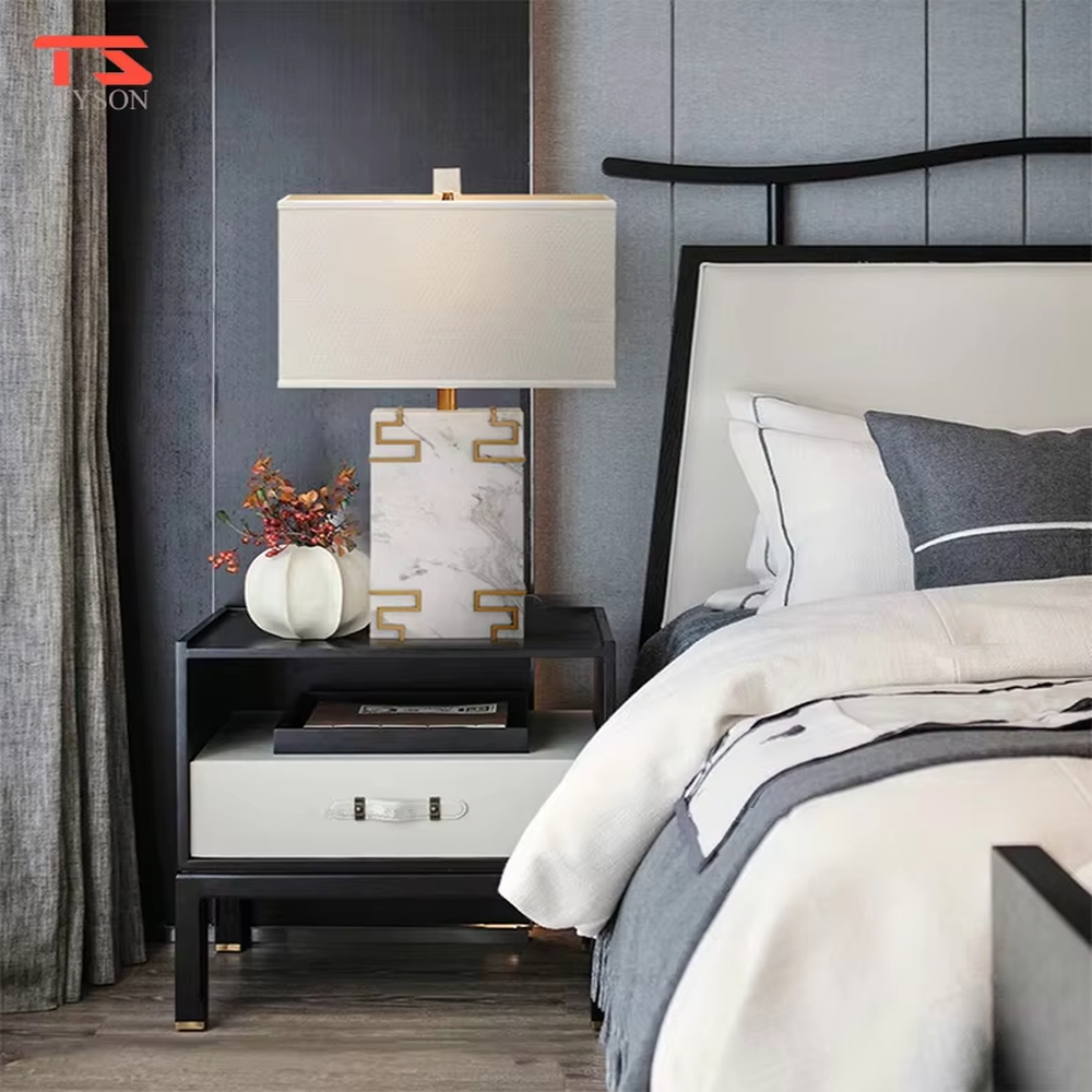 New Chinese light luxury style marble pattern table lamp, with a white faux marble lamp body paired with gold metal fretwork decoration, and a rectangular off-white fabric lampshade. It emits soft and elegant light, combining decorativeness and practicality, suitable for lighting and decoration in spaces such as bedroom nightstands, living room side tables, and New Chinese style show flats.