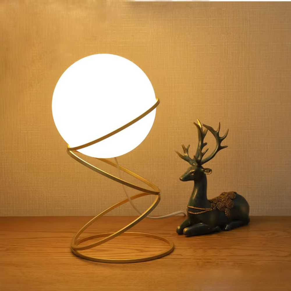 Modern planet orbit-shaped table lamp (white ball + gold ring stand), warm light effect, creating a sci-fi artistic minimalist space atmosphere.