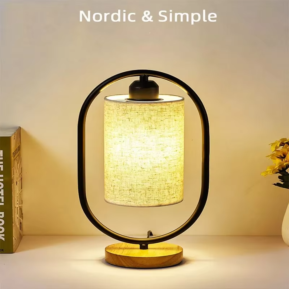 Modern minimalist silver oval metal frame linen texture lampshade wooden base table lamp, warm light effect, creating a cozy minimalist home atmosphere.
