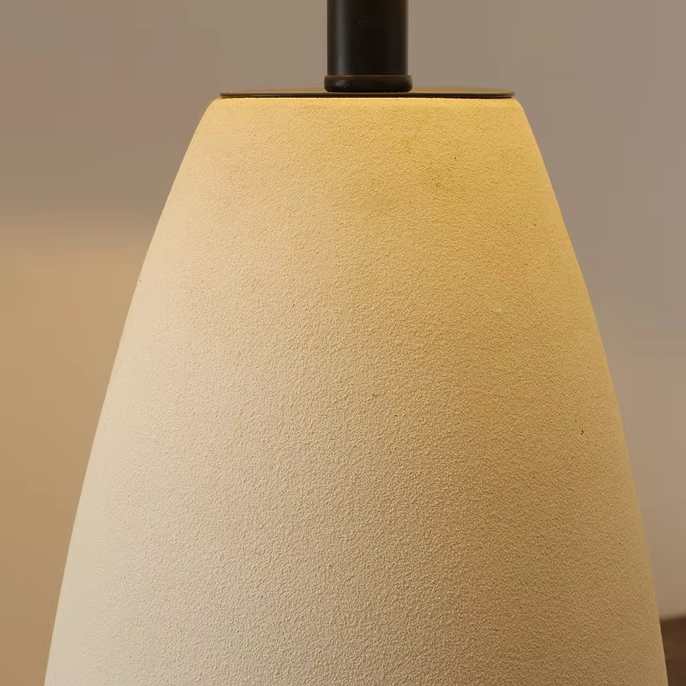This is a wabi-sabi style minimalist table lamp, featuring an off-white frosted ceramic base paired with a linen fabric lampshade. The light is soft and warm, serving both lighting and decorative purposes, suitable for scenarios pursuing a warm and relaxed feeling such as bedroom nightstands, homestay guest rooms, Japanese-style tea rooms, and wabi-sabi style living rooms.