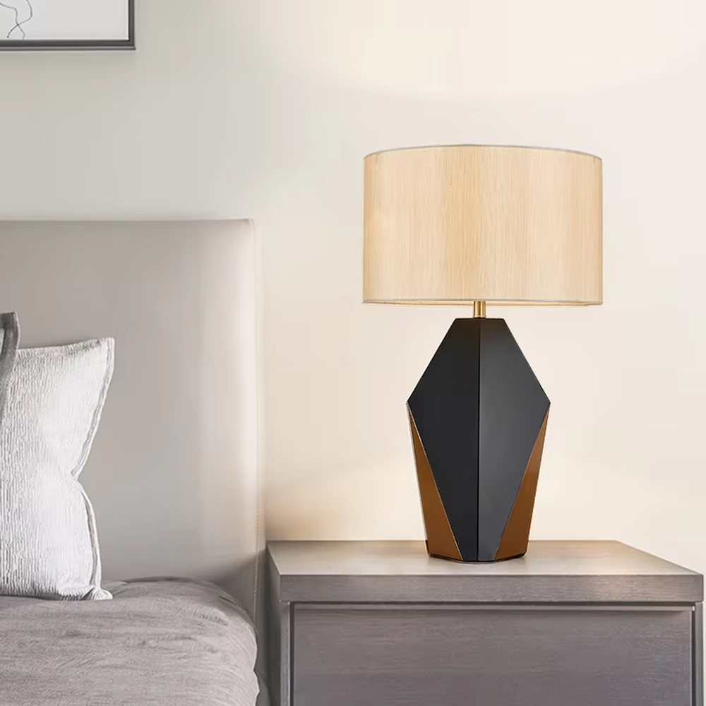 Light luxury black-gold geometric diamond base table lamp, black geometric diamond base + golden decorative details + beige fabric lampshade, soft warm light, creating a high-end light luxury bedroom atmosphere.