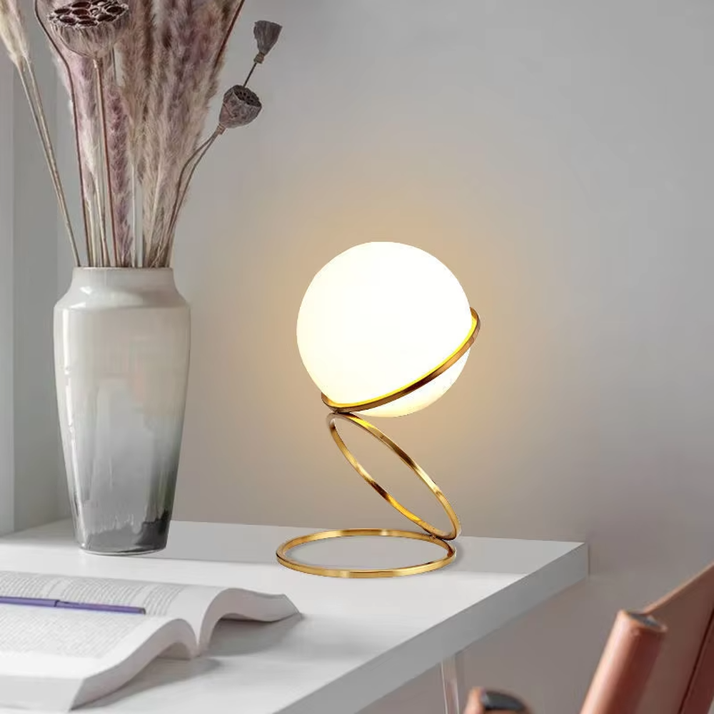 Modern planet orbit-shaped table lamp (white ball + gold ring stand), warm light effect, creating a sci-fi artistic minimalist space atmosphere.