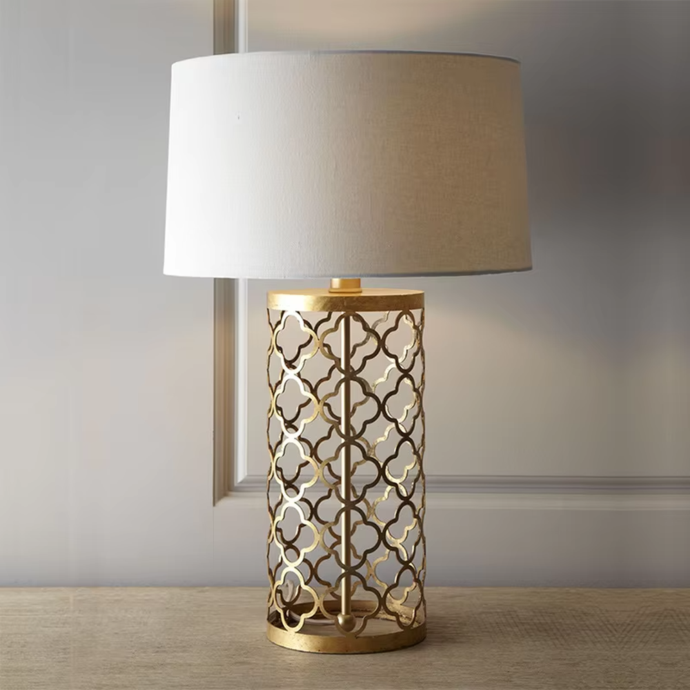 Light luxury golden hollow pattern table lamp (white fabric shade), warm light effect, creating an exquisite retro space atmosphere.
