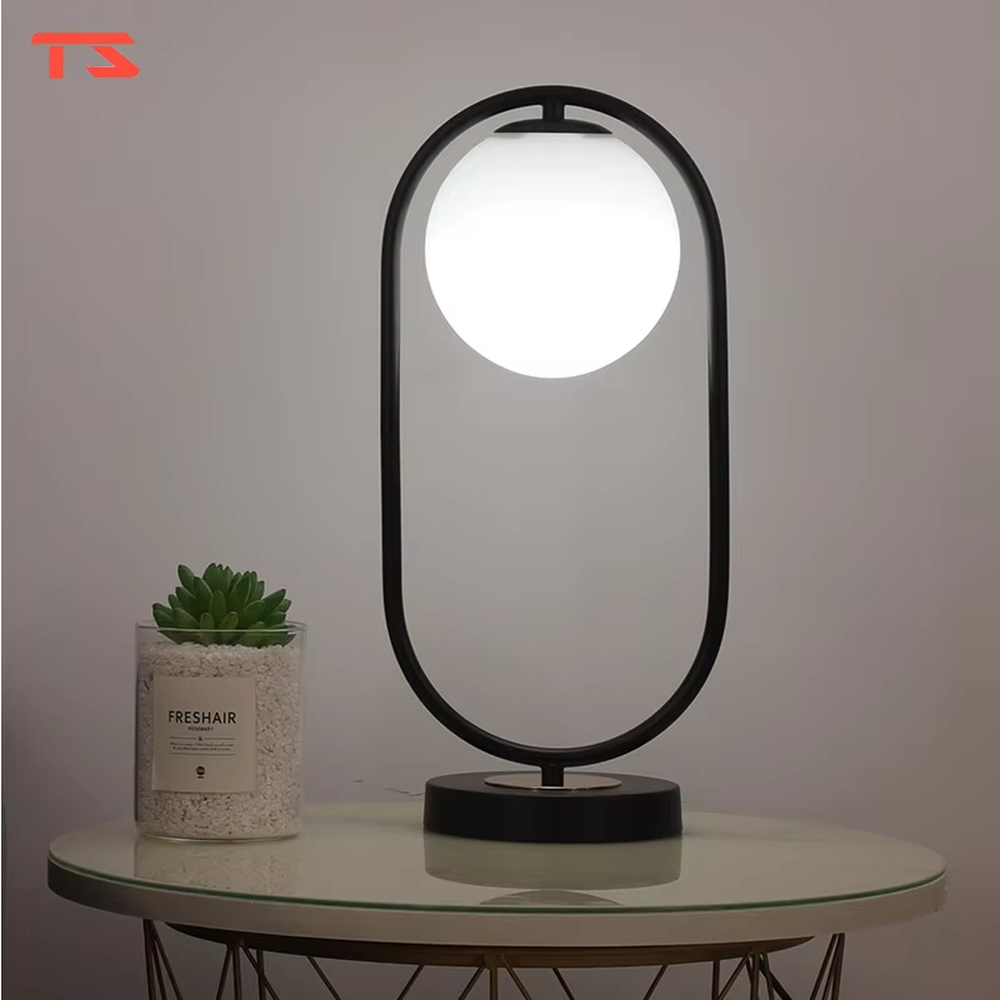 Modern minimalist oval-frame spherical table lamp, with a black metal oval frame paired with a milky white luminous bulb, emitting soft and even light, combining decorativeness and practicality, suitable for lighting and decoration in spaces such as bedroom nightstands, living room side tables, and office desks.