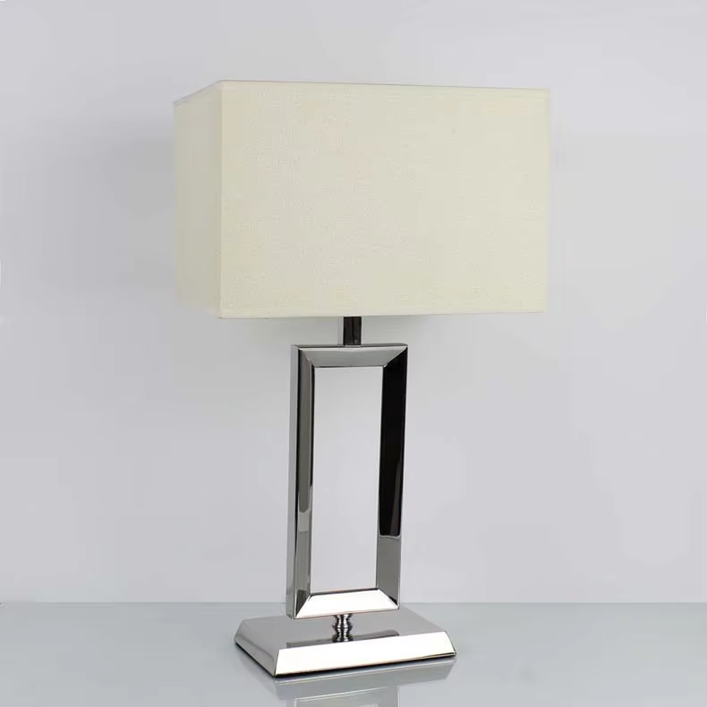 Modern minimalist geometric metal table lamp (bright chrome hollow lamp base + rectangular fabric lampshade), warm light effect, creating an exquisite and high-end home and office atmosphere.