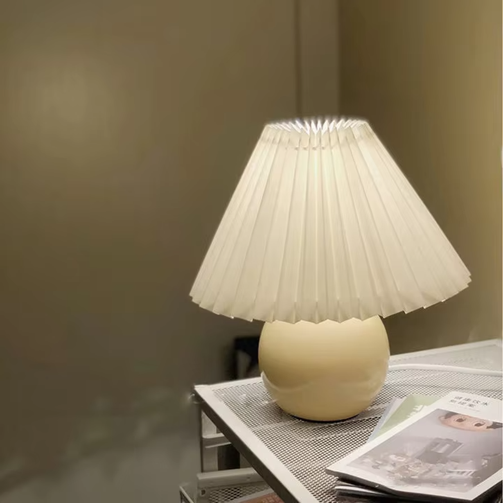 Fresh pleated umbrella shade table lamp (cream yellow glaze ball body + white pleated shade), warm light effect, creating a soft and healing home atmosphere.