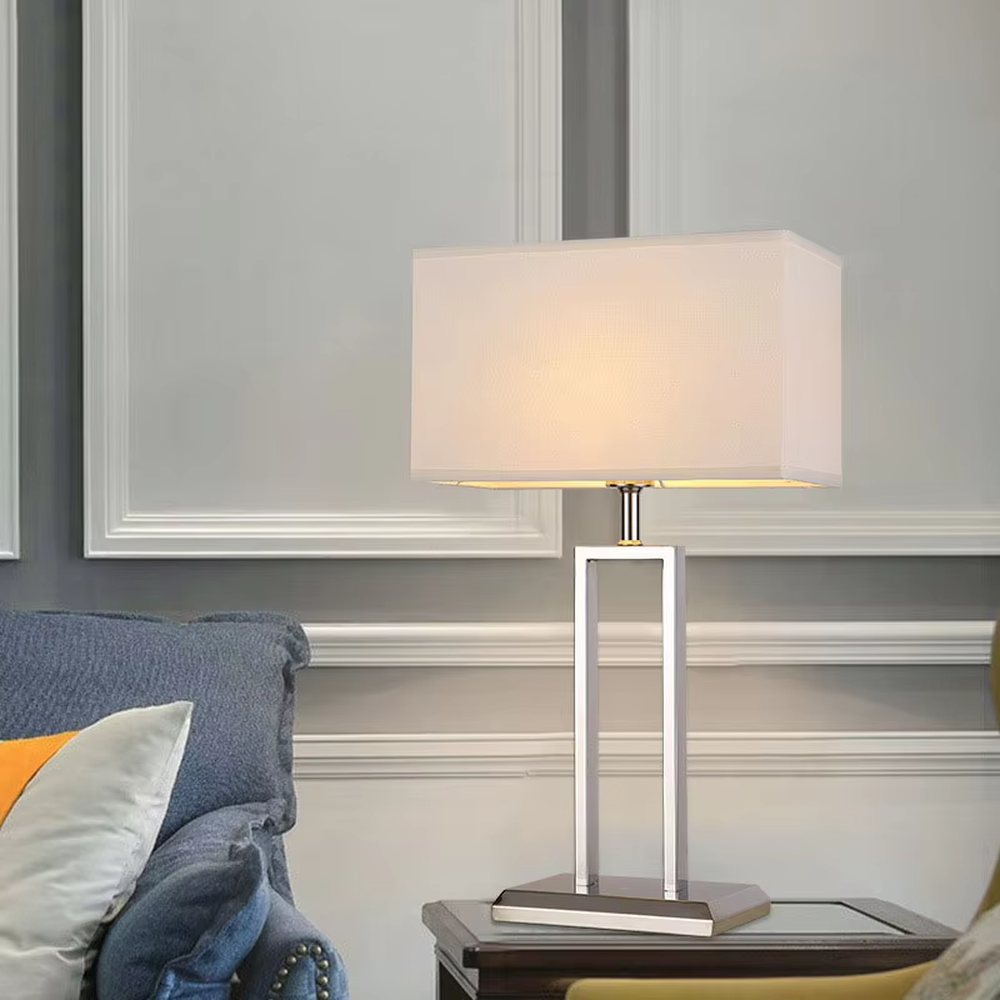Modern minimalist geometric metal table lamp (bright chrome hollow lamp base + rectangular fabric lampshade), warm light effect, creating an exquisite and high-end home and office atmosphere.