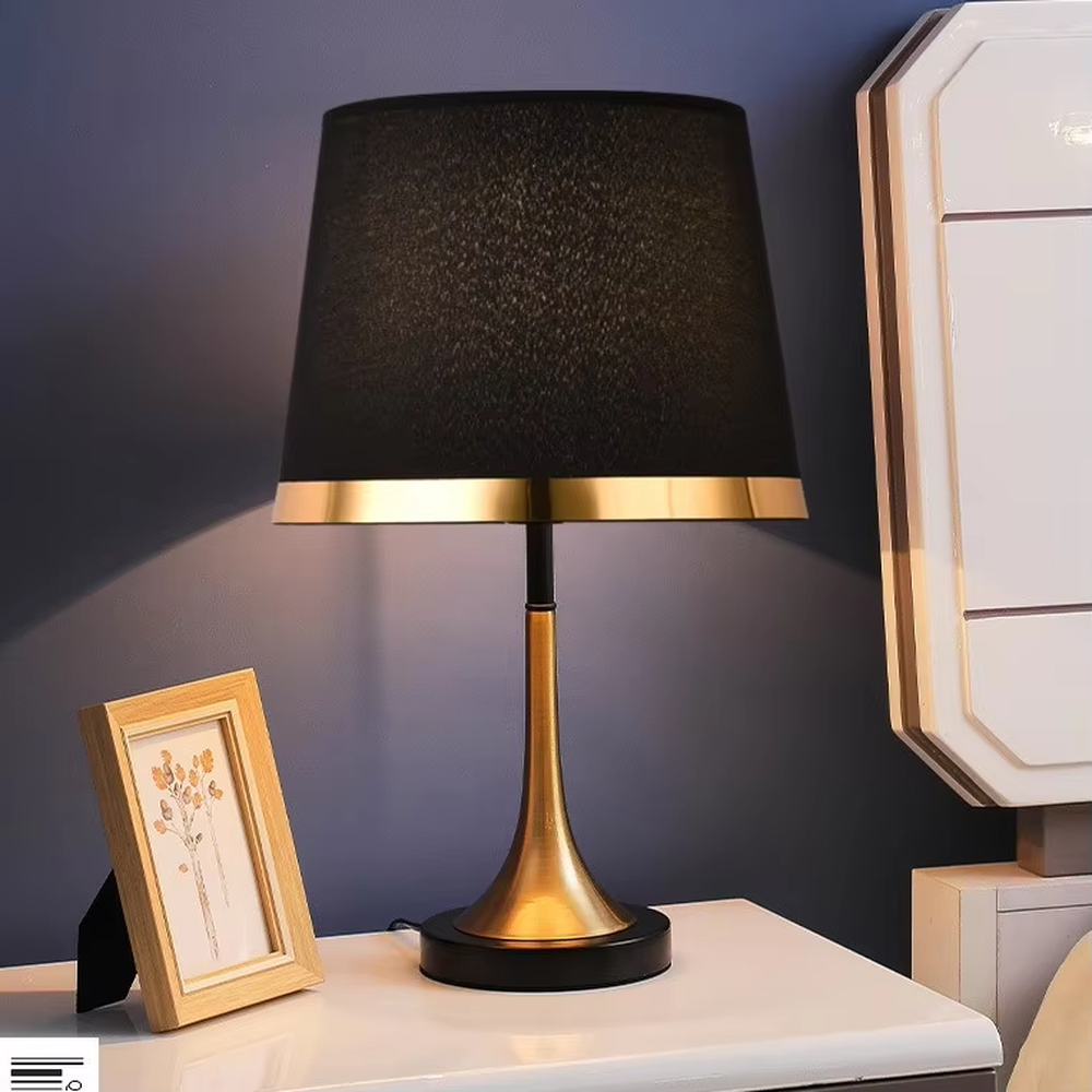 This modern light luxury table lamp features a black fabric cylindrical lampshade, paired with a black and gold contrasting metal lamp pole. The lower part is a trumpet-shaped gold metal design, and the base is black. The overall style is simple and elegant, with soft, non-glaring light, serving both lighting and decorative purposes, suitable for bedrooms, studies, living rooms and other spaces.
