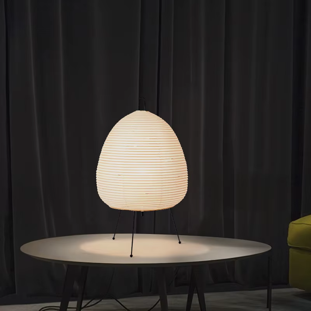 This wabi-sabi style egg-shaped table lamp features a striped light-transmitting paper lampshade, supported by a black metal tripod, with a simple and soft shape, serving both lighting and decorative purposes, ideal for bedroom bedside tables, homestay rooms, wabi-sabi style spaces and other scenarios.
