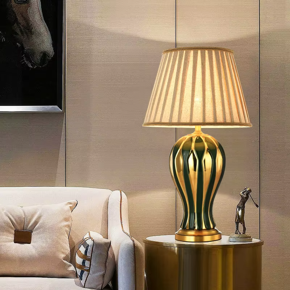 European-style light luxury ceramic table lamp, with a green-gold gradient wavy ceramic base, off-white pleated fabric lampshade and gold metal details, providing soft and warm light, designed to enhance the retro and elegant atmosphere of spaces, suitable for bedroom nightstands, living room side tables, European-style homes and hotel guest rooms, etc.