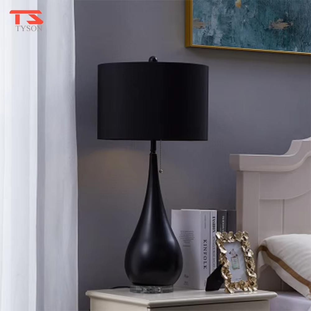 This is a pastoral-style floral fabric table lamp, with an off-white lampshade printed with blue and black floral patterns, paired with a black matte teardrop-shaped base and transparent crystal feet, featuring both decorative and lighting functions, ideal for warm indoor scenarios such as bedroom nightstands and living room side tables.
