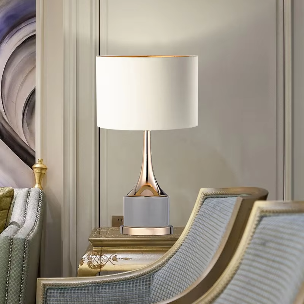 Light luxury gray-gold fabric lampshade metal base table lamp (gray fabric shade + gold pole + gray stone-pattern base), warm light effect, creating an exquisite and elegant atmosphere.