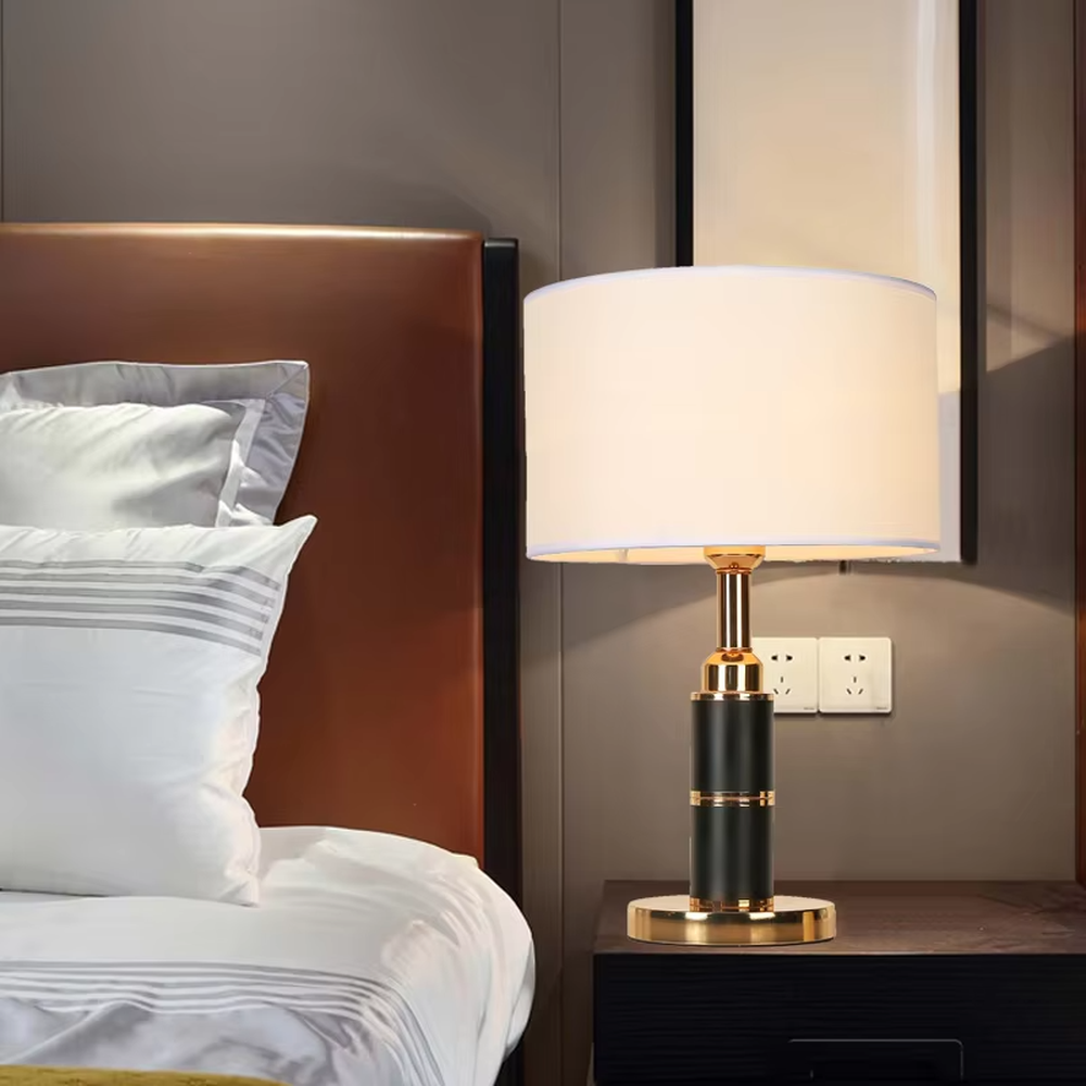 Light luxury black-gold cylindrical base table lamp, black main column + golden metal decorations + beige fabric lampshade, soft warm light creates a high-end home atmosphere.