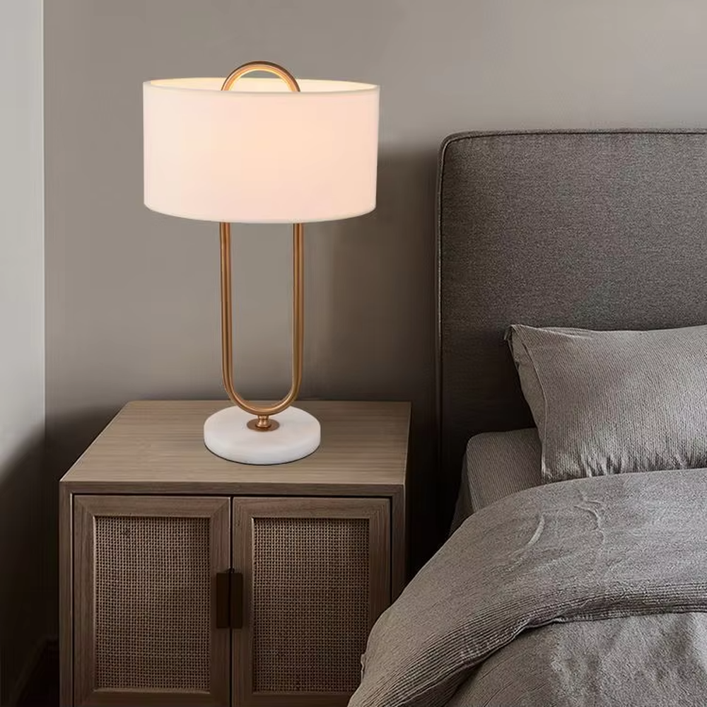 This modern light luxury table lamp features a U-shaped frame made of gold metal, paired with a white fabric rectangular lampshade and a white marble base, with a simple and elegant shape. It serves both lighting and decorative purposes, ideal for light luxury spaces such as bedroom bedside tables, living room side tables, and hotel guest rooms.
