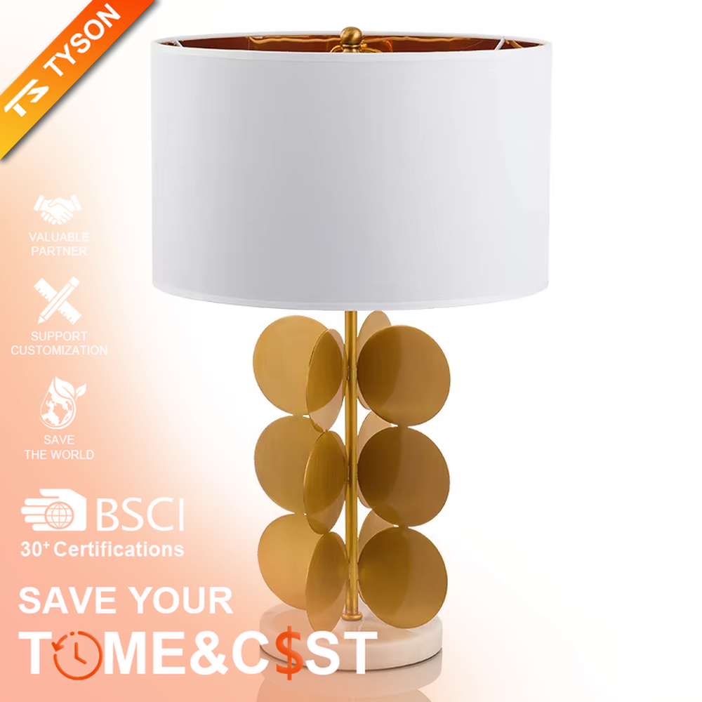 This light luxury table lamp features a white fabric cylindrical lampshade on top, a lamp post with a staggered stack of gold metal discs, and a white marble base, serving both lighting and decorative purposes, ideal for living room side tables, bedroom bedside tables, light luxury homestays and other spaces.