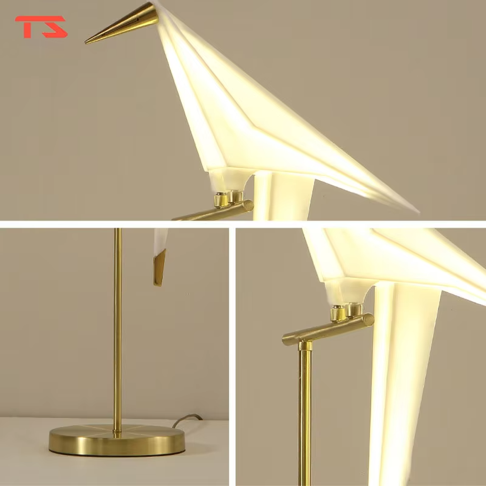 This is a modern light luxury origami crane-shaped table lamp, featuring a gold metal stand paired with a translucent paper art lamp body. The lamp body is as dynamic and soft as an origami crane, serving both lighting and artistic decoration purposes, suitable for bedroom nightstands, light luxury living room side tables, hotel guest rooms, showrooms and other scenarios.