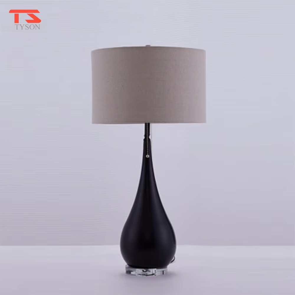 This is a pastoral-style floral fabric table lamp, with an off-white lampshade printed with blue and black floral patterns, paired with a black matte teardrop-shaped base and transparent crystal feet, featuring both decorative and lighting functions, ideal for warm indoor scenarios such as bedroom nightstands and living room side tables.