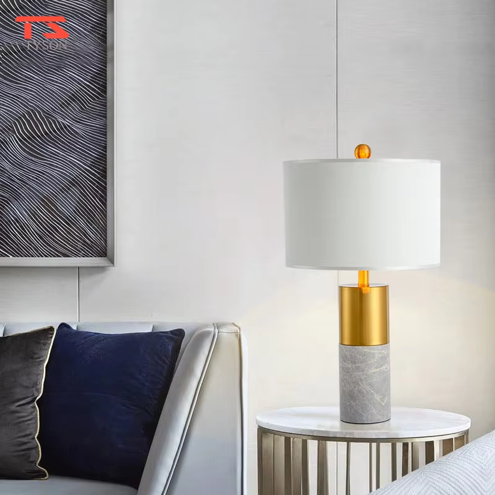 This is a light luxury marble-metal splicing table lamp, with a white fabric lampshade paired with a base made of gold metal and gray marble, accented with an orange decorative ball on top, featuring both decorative and lighting functions, ideal for high-end indoor scenarios such as bedroom nightstands and living room side tables.