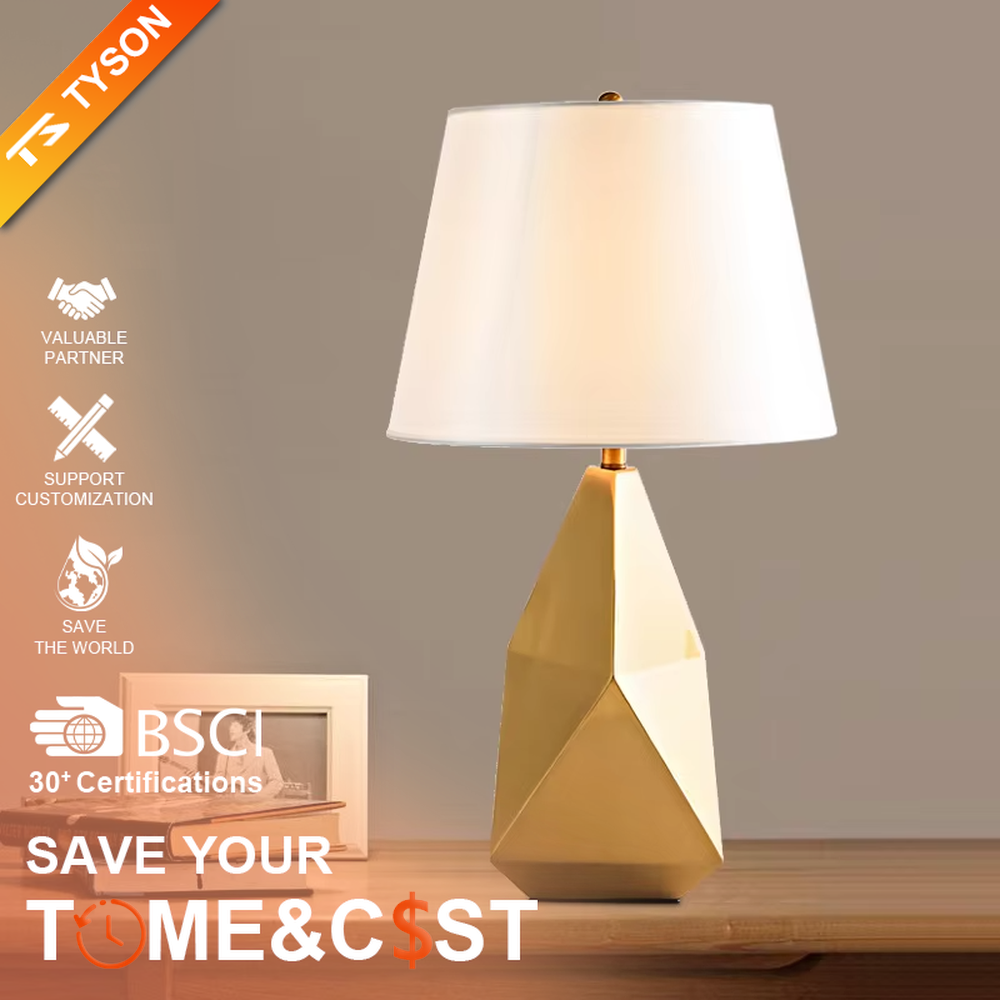 Modern light luxury style geometric cut metal table lamp, featuring a gold rhombus lamp body paired with an off-white fabric lampshade (with a gold trim at the bottom), designed for both tabletop placement and hanging. It emits soft and warm light, combining decorativeness and practicality, suitable for lighting and decoration in spaces such as living room side tables, bedroom nightstands, and hotel guest rooms.