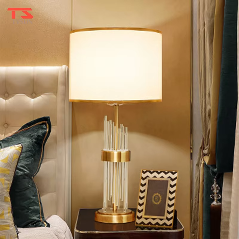 This is a light luxury crystal-metal splicing table lamp, with an off-white fabric lampshade edged with gold trim, a lamp post made of transparent crystal strips and gold metal, and a gold metal base, featuring both decorative and lighting functions, ideal for high-end indoor scenarios such as bedroom nightstands and living room side tables.