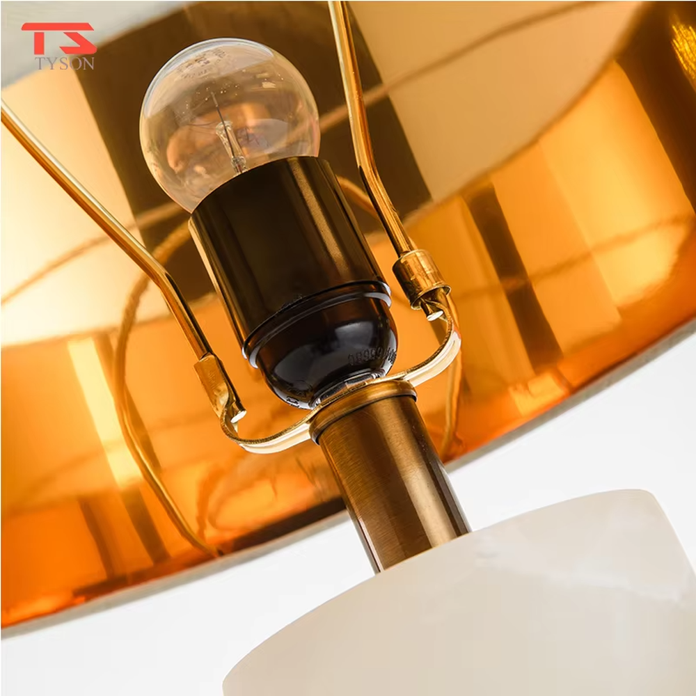 This is a light luxury minimalist table lamp, featuring a natural marble lamp post paired with gold metal accents and an off-white fabric lampshade. It emits soft and gentle light, serving both lighting and decorative purposes, suitable for bedroom nightstands, hotel guest rooms, light luxury living room side tables, showrooms and other scenarios.