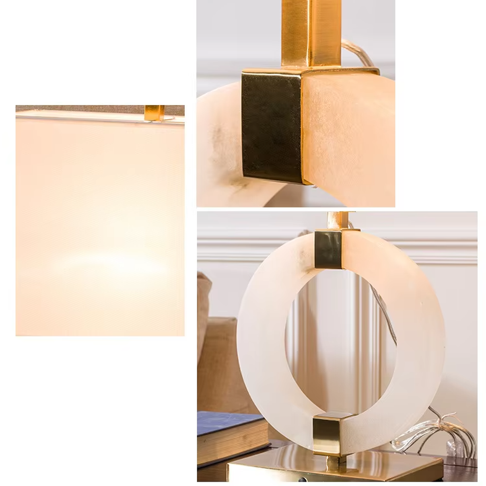 Modern light luxury style table lamp with a white natural stone/acrylic ring paired with gold metal brackets and base, and a rectangular white fabric lampshade. It emits soft and even light, combining decorativeness and practicality, suitable for lighting and decoration in spaces such as bedroom nightstands, living room side tables, and hotel guest rooms.