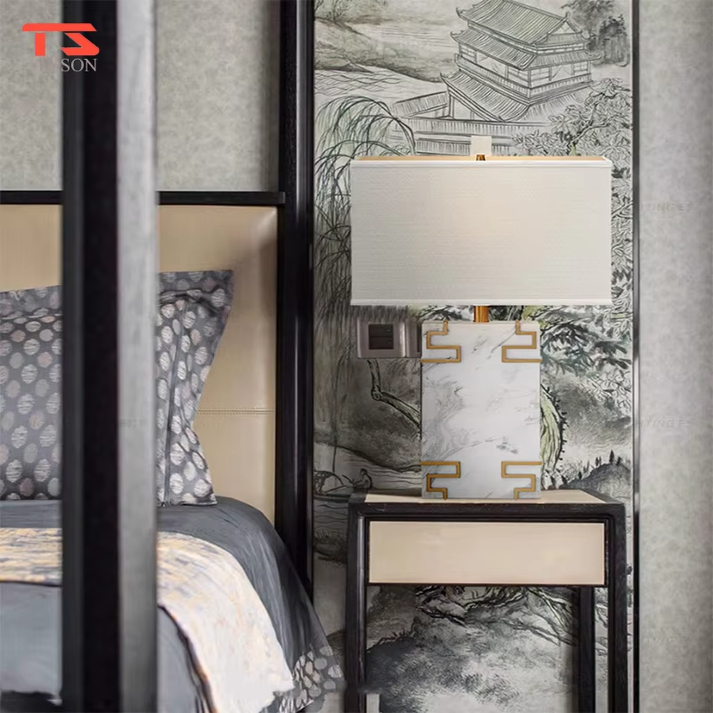 New Chinese light luxury style marble pattern table lamp, with a white faux marble lamp body paired with gold metal fretwork decoration, and a rectangular off-white fabric lampshade. It emits soft and elegant light, combining decorativeness and practicality, suitable for lighting and decoration in spaces such as bedroom nightstands, living room side tables, and New Chinese style show flats.