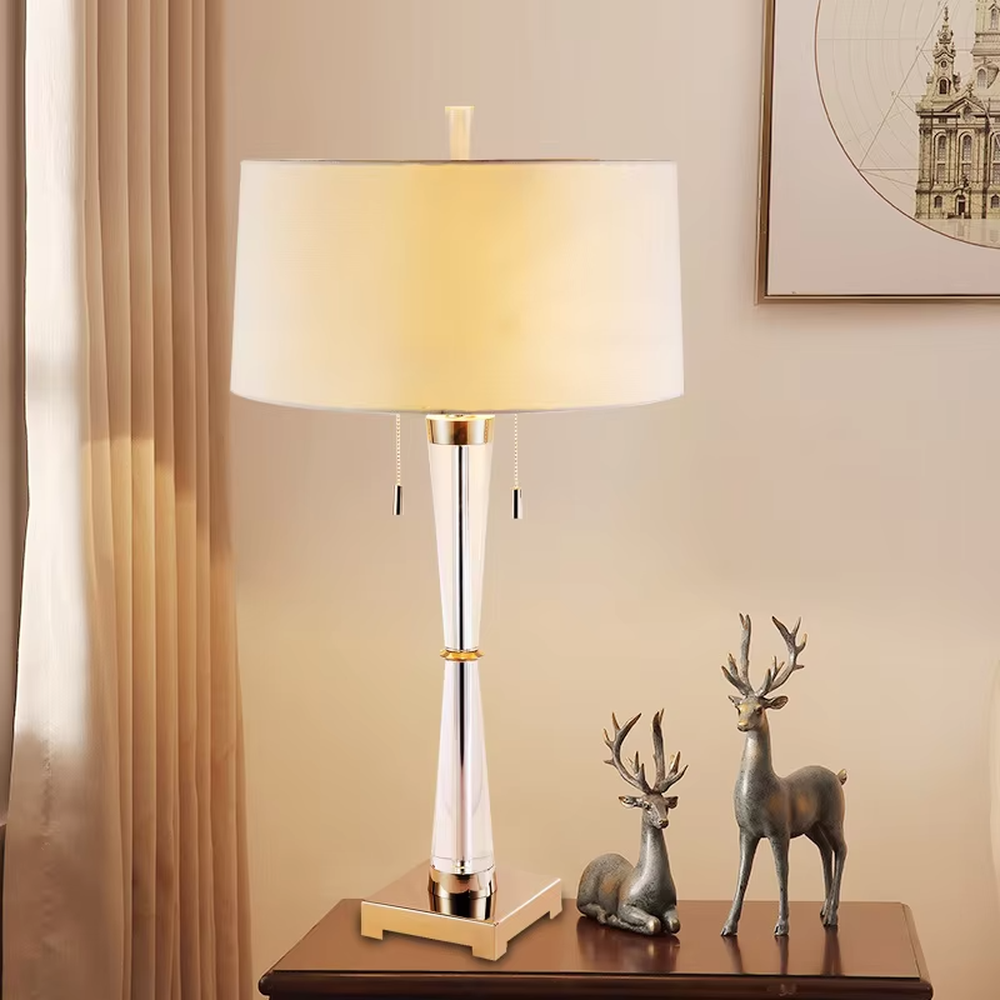Modern light luxury fabric table lamp, with an off-white fabric lampshade paired with a transparent acrylic + gold metal spliced conical lamp pole, a gold square base with a double pull-cord switch, emitting soft and warm light, combining decorativeness and practicality, suitable for lighting and decoration in spaces such as bedroom nightstands, living room side tables, and hotel guest rooms.