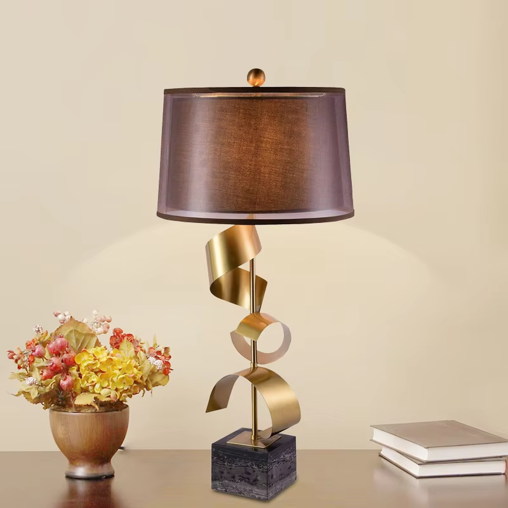 Light luxury spiral metal table lamp (gold spiral pole + pink-brown fabric shade), warm light effect, creating a dynamic and high-end warm space atmosphere.