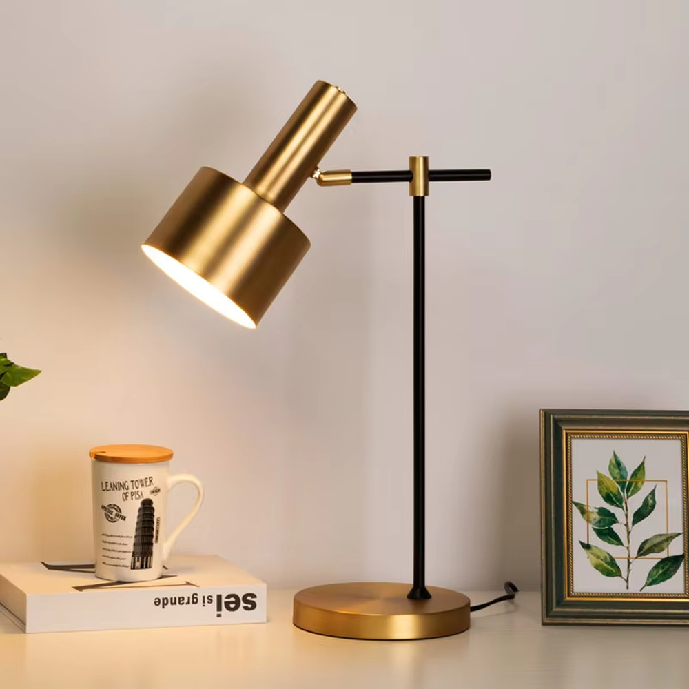 Modern light luxury black-gold adjustable metal table lamp, golden lampshade + black-gold stand + round golden base, angle-adjustable, soft warm light, creating a simple high-end office/home atmosphere.