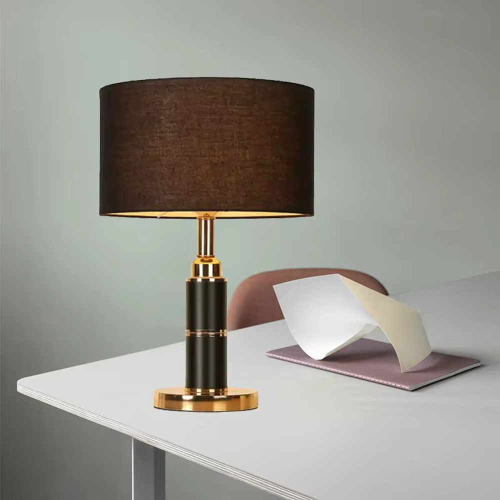 Light luxury black-gold cylindrical base table lamp, black main column + golden metal decorations + beige fabric lampshade, soft warm light creates a high-end home atmosphere.