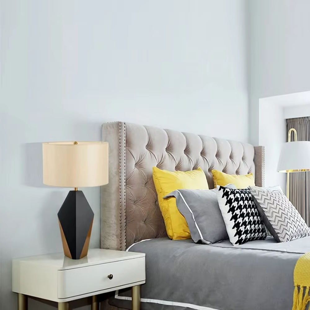 Light luxury black-gold geometric diamond base table lamp, black geometric diamond base + golden decorative details + beige fabric lampshade, soft warm light, creating a high-end light luxury bedroom atmosphere.