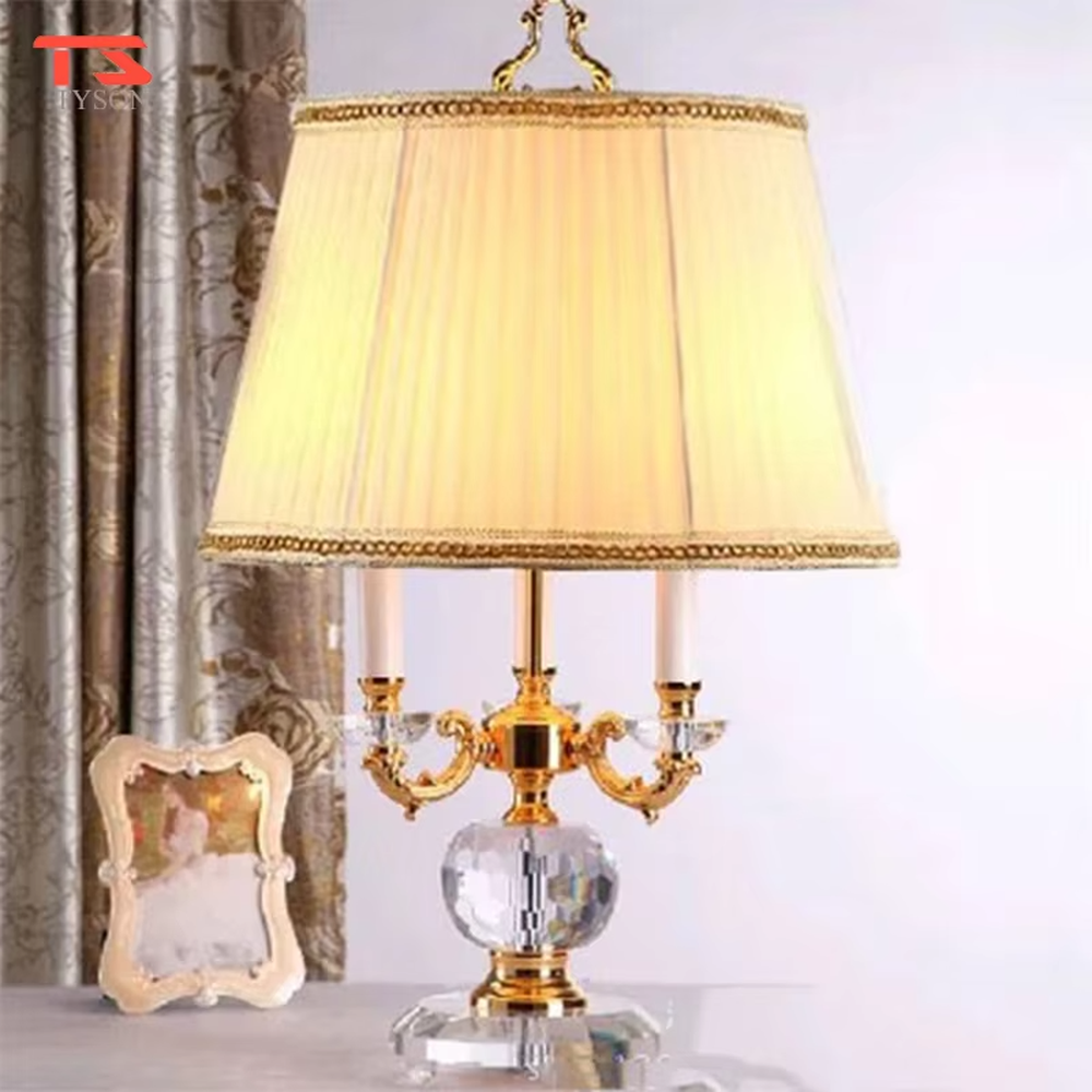 This European court-style table lamp features a carved lamp frame made of glossy gold metal, paired with a crystal ball base and a pleated fabric lampshade (trimmed with gold edging). It presents a luxurious and retro texture, with soft and warm light, serving both lighting and decorative purposes, suitable for European-style bedrooms, villa guest rooms and other spaces.