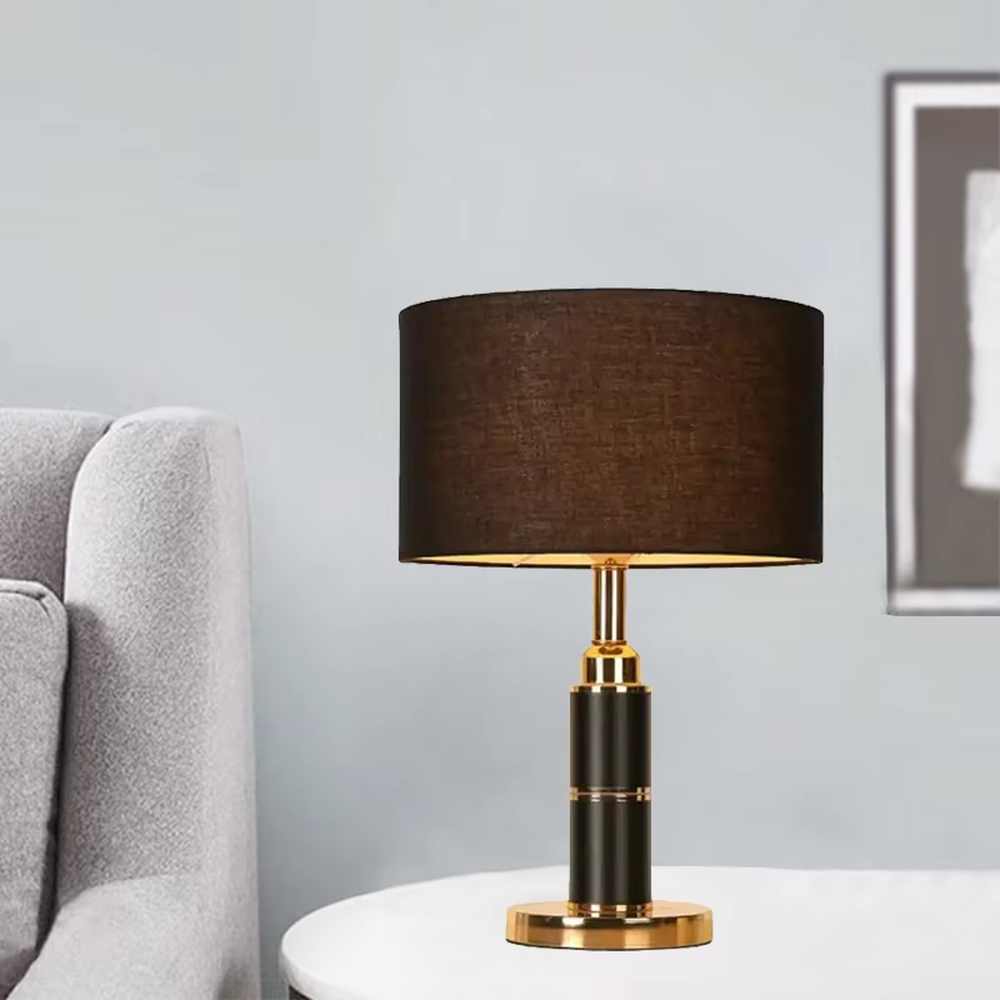 Light luxury brown fabric shade black-gold cylindrical base table lamp, warm light effect, creating a calm and high-end space atmosphere.