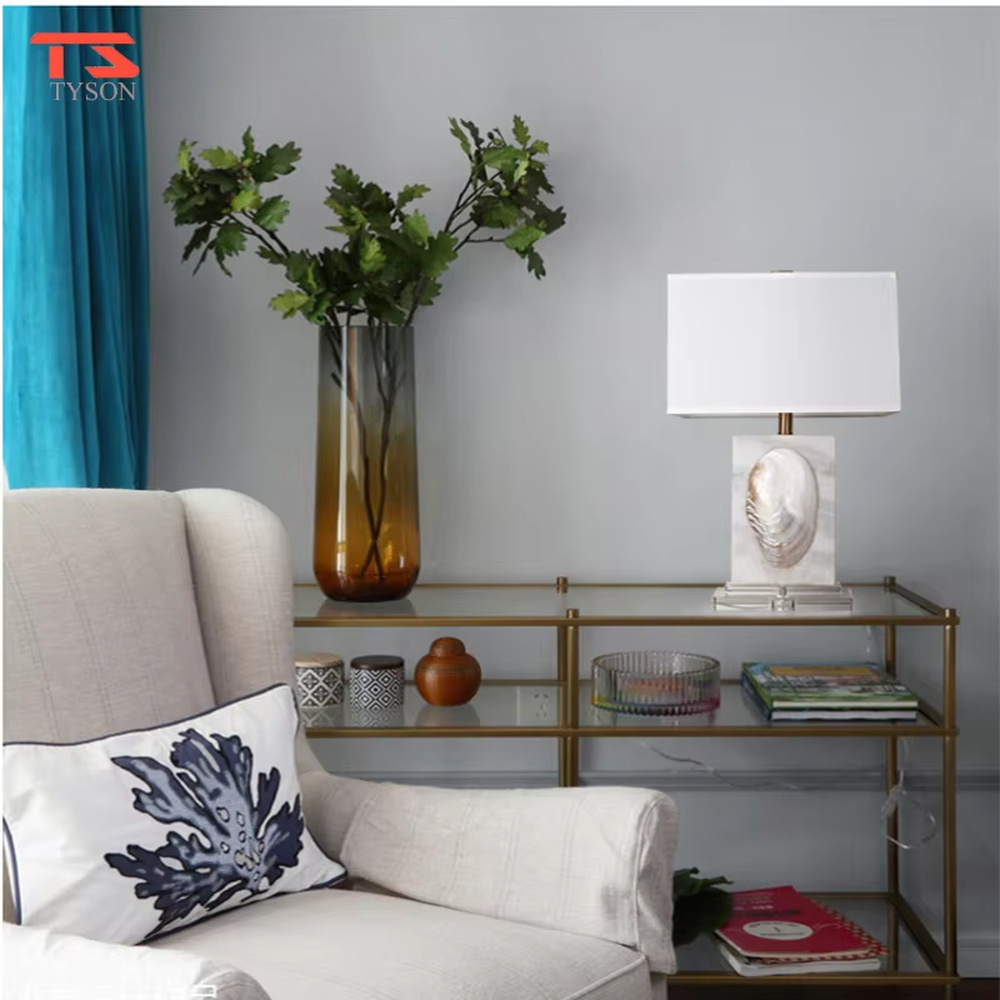 This light luxury modern table lamp features a light-colored stone base with shell relief, paired with gold metal connectors and an off-white fabric rectangular lampshade. It serves both lighting and decorative purposes, ideal for light luxury spaces such as bedroom bedside tables, living room side tables, and hotel guest rooms.