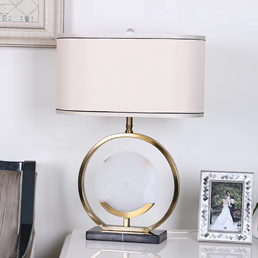 Modern light luxury gold ring white spherical base beige trimmed fabric shade table lamp, warm light effect, creating an elegant home atmosphere.
