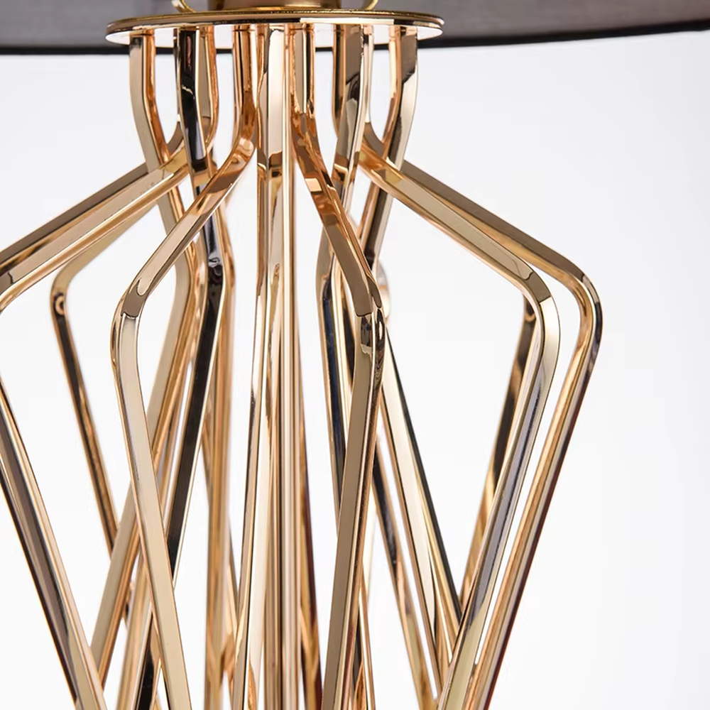 Modern luxurious black-gold geometric interwoven metal stand table lamp (black fabric lampshade + golden interwoven poles + black base), warm light effect, creating a high-end artistic atmosphere.