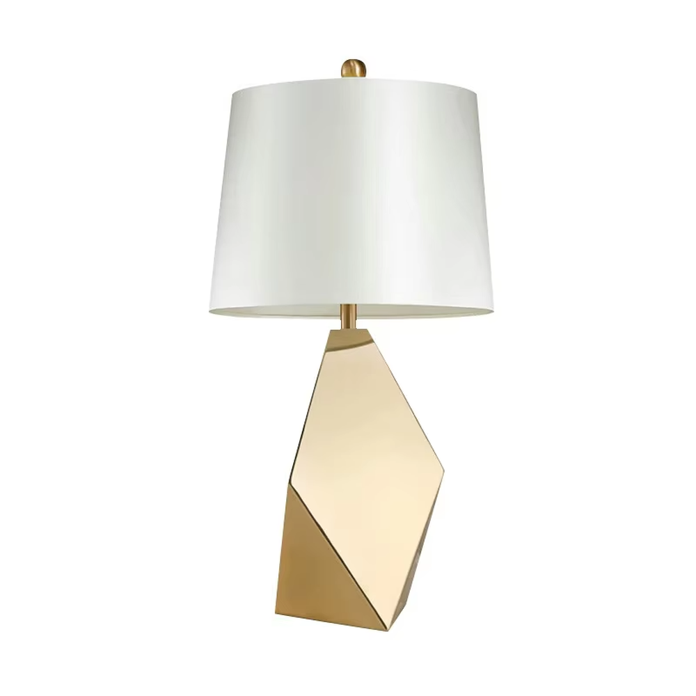 Modern light luxury style geometric cut metal table lamp, featuring a gold rhombus lamp body paired with an off-white fabric lampshade (with a gold trim at the bottom), designed for both tabletop placement and hanging. It emits soft and warm light, combining decorativeness and practicality, suitable for lighting and decoration in spaces such as living room side tables, bedroom nightstands, and hotel guest rooms.