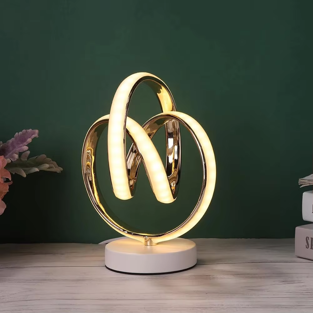 This light luxury art table lamp features a "8"/infinity symbol shape made of gold metal, with embedded LED light strips and a white marble base, serving both lighting and decorative purposes, ideal for living room side tables, bedroom bedside tables, light luxury homestays and other spaces.