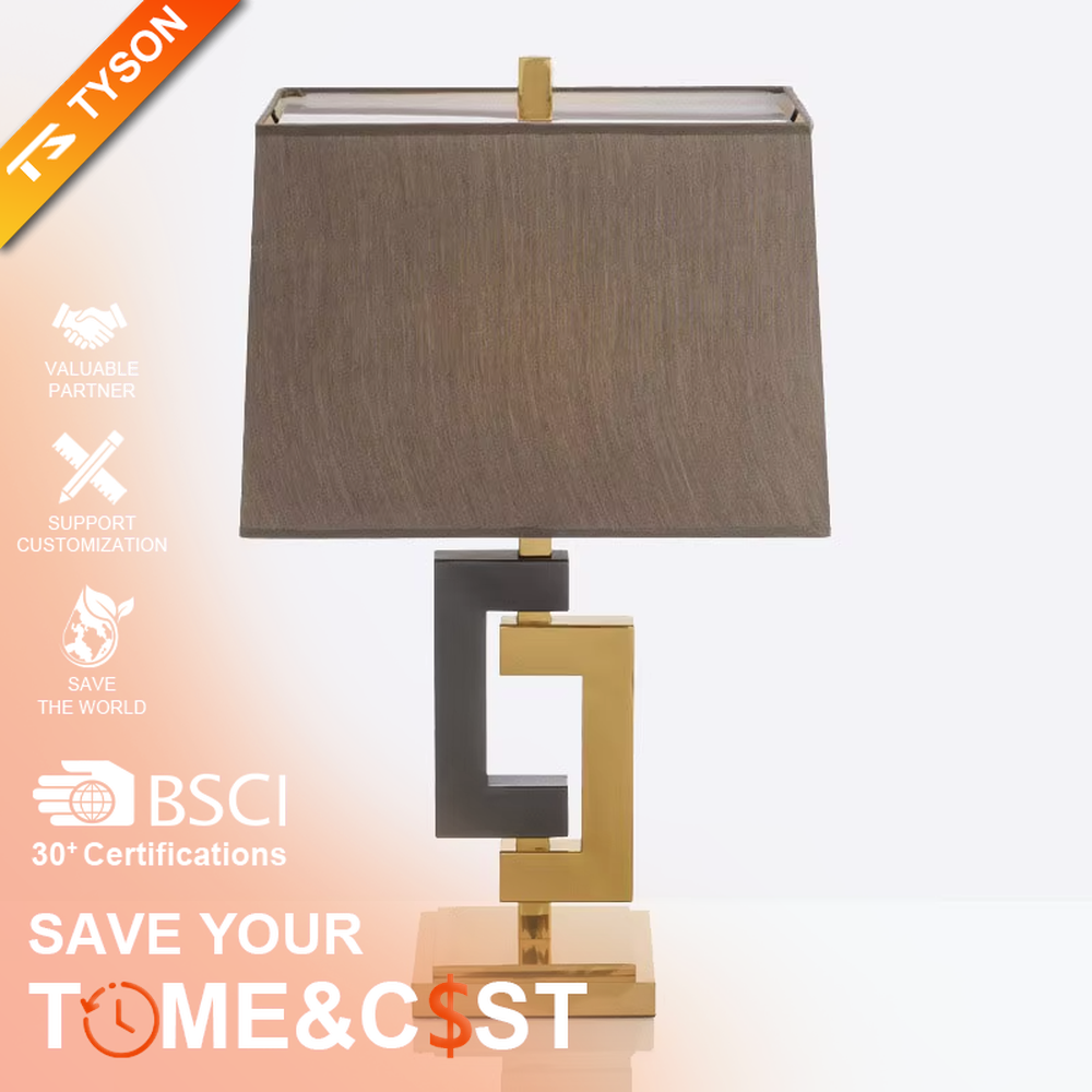 This is a modern light luxury geometric interlocking table lamp, featuring an interlocking geometric lamp body crafted from gold and gray dual-color metal, paired with a dark gray fabric lampshade. It emits soft and uniform light, serving both lighting and decorative purposes, suitable for bedroom nightstands, light luxury living room side tables, hotel guest rooms, showrooms and other scenarios.