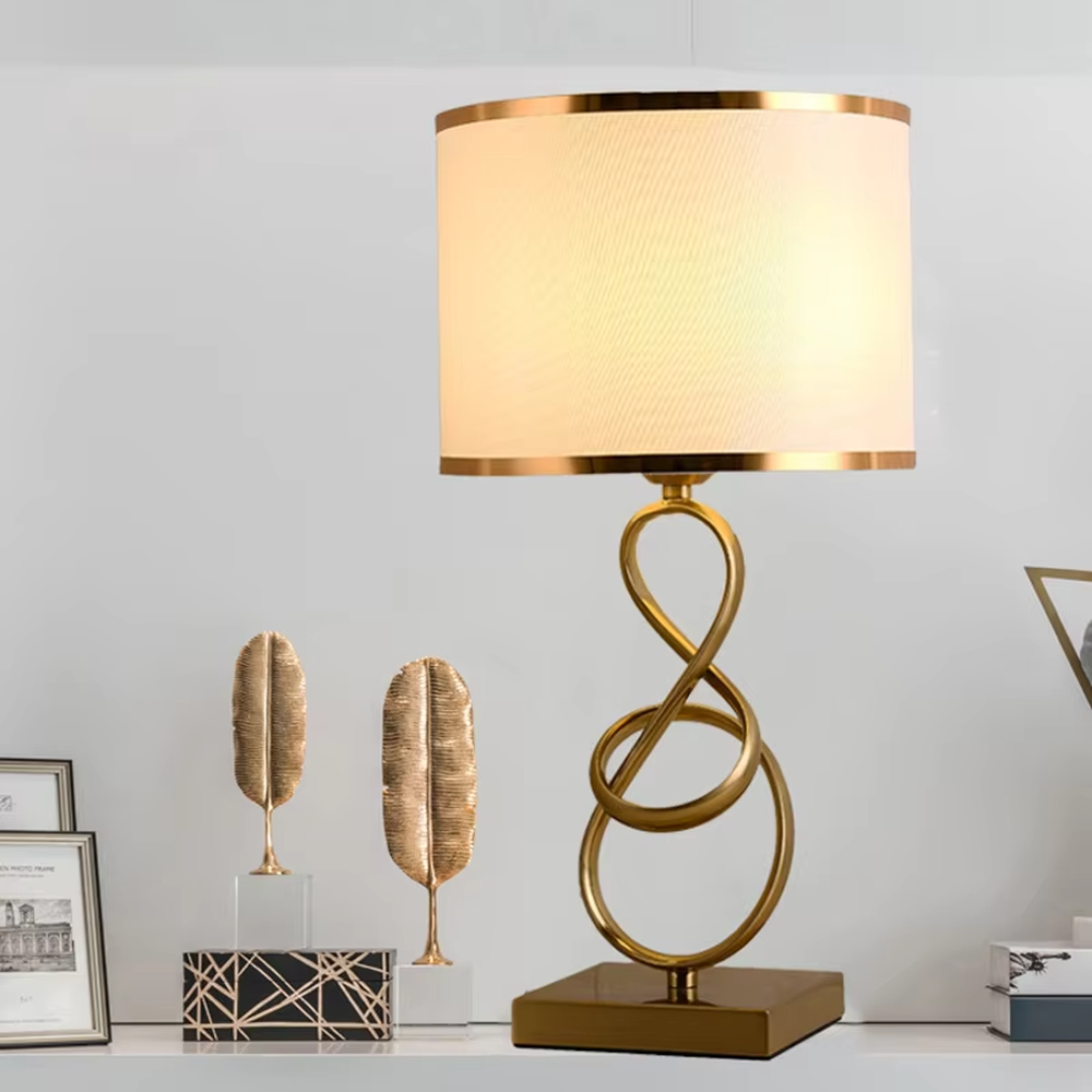 Modern light luxury twisted line metal table lamp, with a gold twisted line lamp pole paired with a beige fabric lampshade (with gold trim on the edge), a square gold base, emitting soft and warm light, combining decorativeness and practicality, suitable for lighting and decoration in spaces such as bedroom nightstands, living room side tables, and studies.