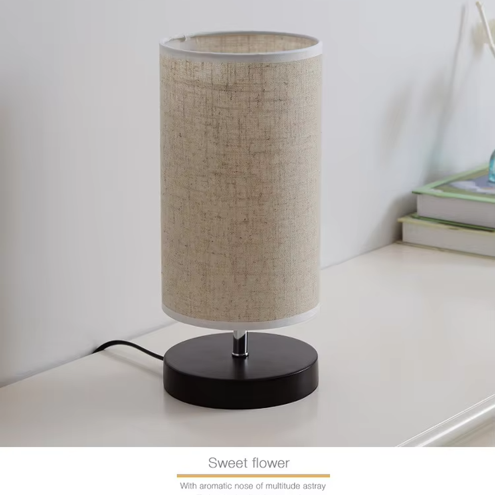 This is a minimalist square fabric table lamp, featuring a light beige linen lampshade paired with a black solid wood base. It emits soft and warm light, serving both lighting and decorative purposes, suitable for bedroom nightstands, desks, homestay guest rooms, living room side tables and other scenarios.