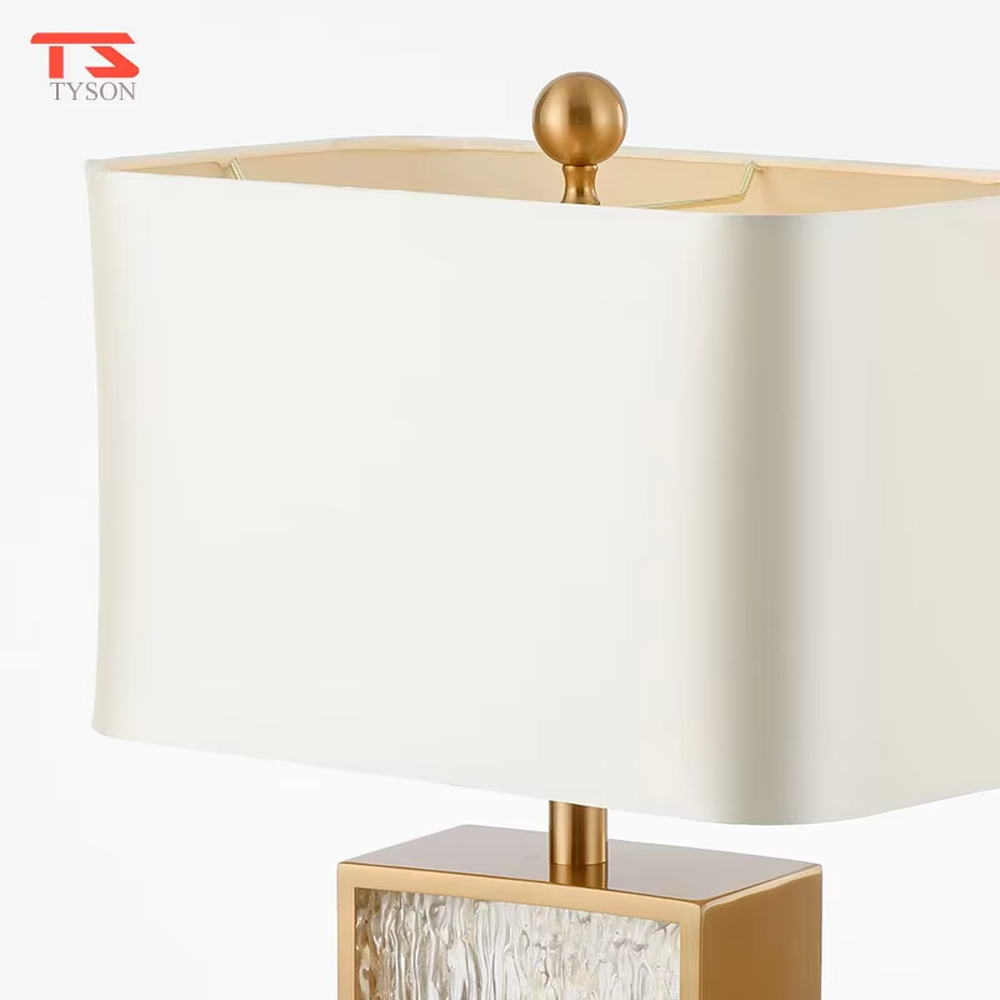 This modern light luxury table lamp features a gold metal frame, paired with a water-textured transparent glass lamp body and a white fabric rectangular lampshade. It serves both lighting and decorative purposes, ideal for light luxury spaces such as bedroom bedside tables, living room side tables, and hotel guest rooms.