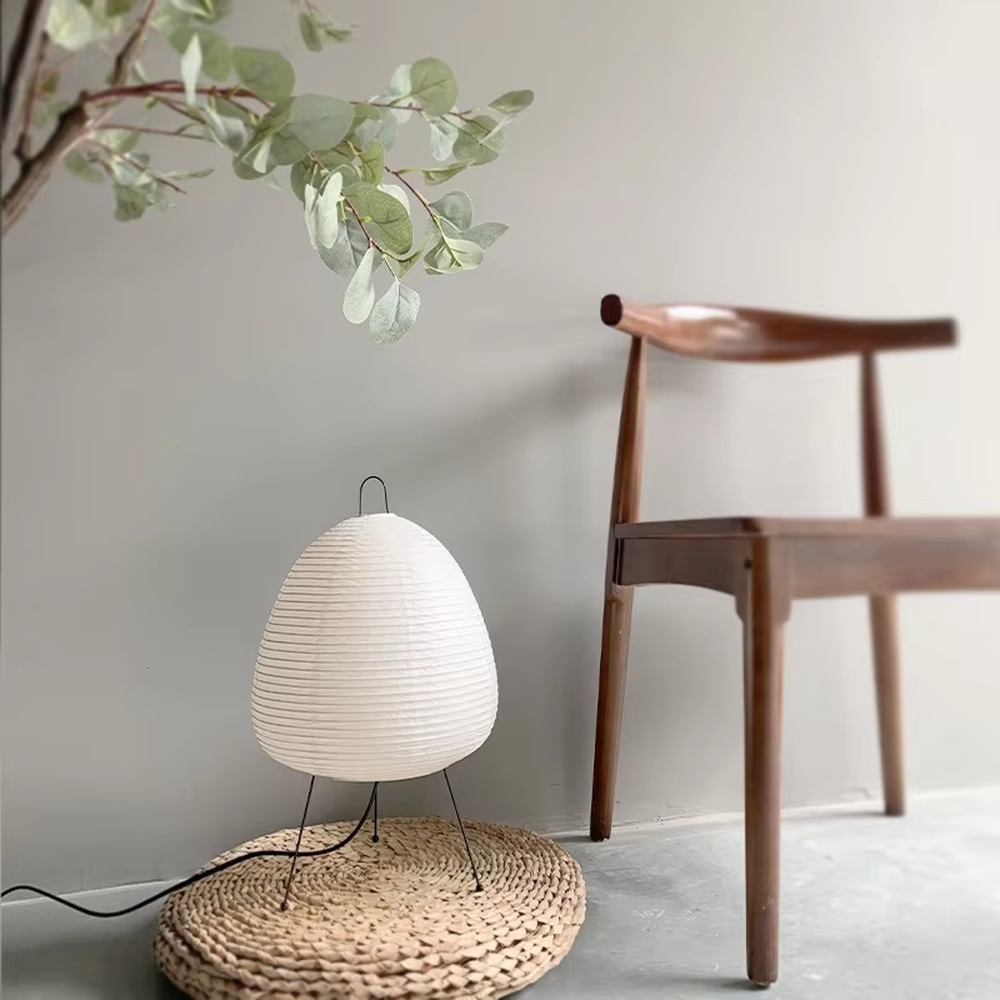 This wabi-sabi style egg-shaped table lamp features a striped light-transmitting paper lampshade, supported by a black metal tripod, with a simple and soft shape, serving both lighting and decorative purposes, ideal for bedroom bedside tables, homestay rooms, wabi-sabi style spaces and other scenarios.