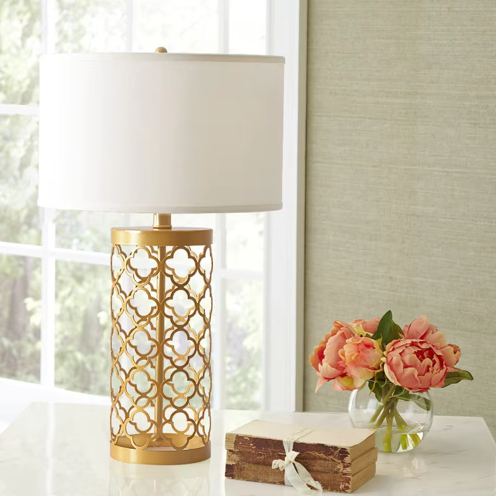Light luxury golden hollow pattern table lamp (white fabric shade), warm light effect, creating an exquisite retro space atmosphere.