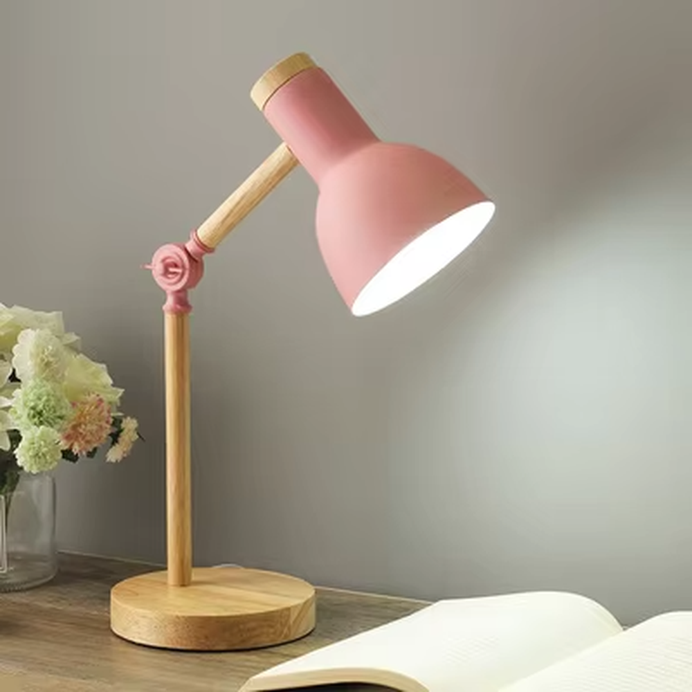 This Nordic-style eye-caring table lamp features a solid wood arm and base, paired with a pink metal conical lampshade, with a rose-shaped decorative joint that supports multi-angle adjustment, serving both lighting and decorative purposes, ideal for studies, children's rooms, bedrooms and other spaces.