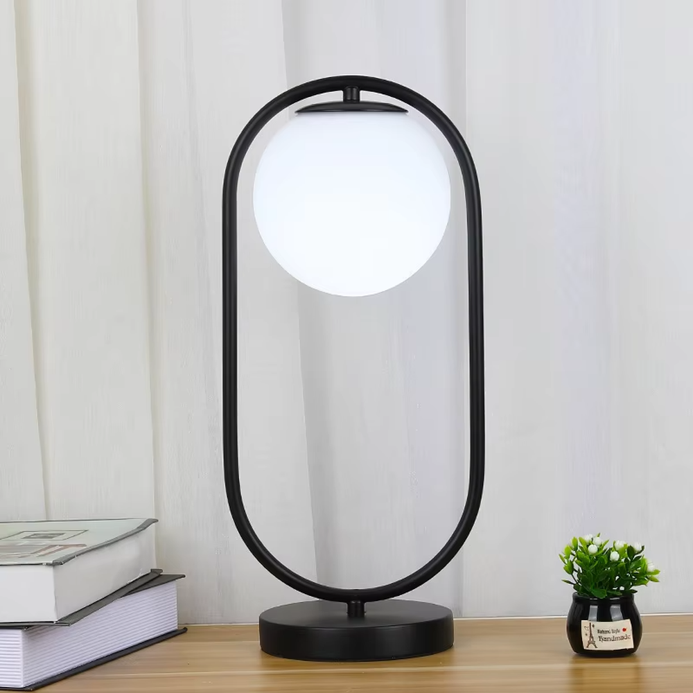 This is a modern minimalist metal frame table lamp, with a black oval metal stand paired with a white spherical frosted lampshade, featuring a simple and elegant design, both decorative and lighting functions, ideal for modern indoor scenarios such as desks and nightstands.