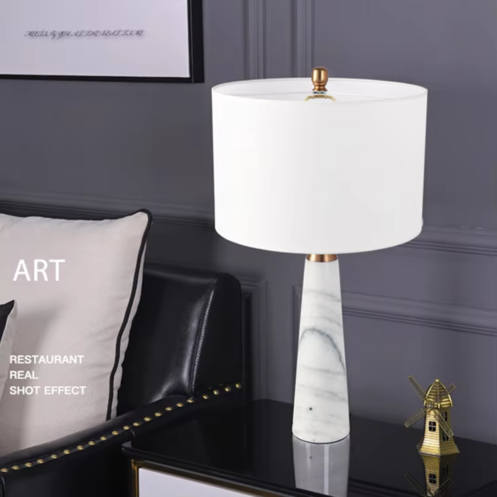 Light luxury marble cone table lamp, with a grey natural marble base, gold metal connection, off-white fabric lampshade with black trim, providing soft and warm light, designed to enhance the delicate texture of spaces, suitable for bedroom nightstands, living room side tables, modern light luxury homes and hotel guest rooms, etc.