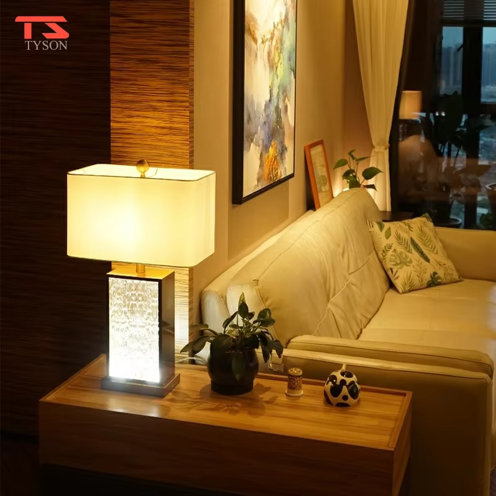 This modern light luxury table lamp features a gold metal frame, paired with a water-textured transparent glass lamp body and a white fabric rectangular lampshade. It serves both lighting and decorative purposes, ideal for light luxury spaces such as bedroom bedside tables, living room side tables, and hotel guest rooms.